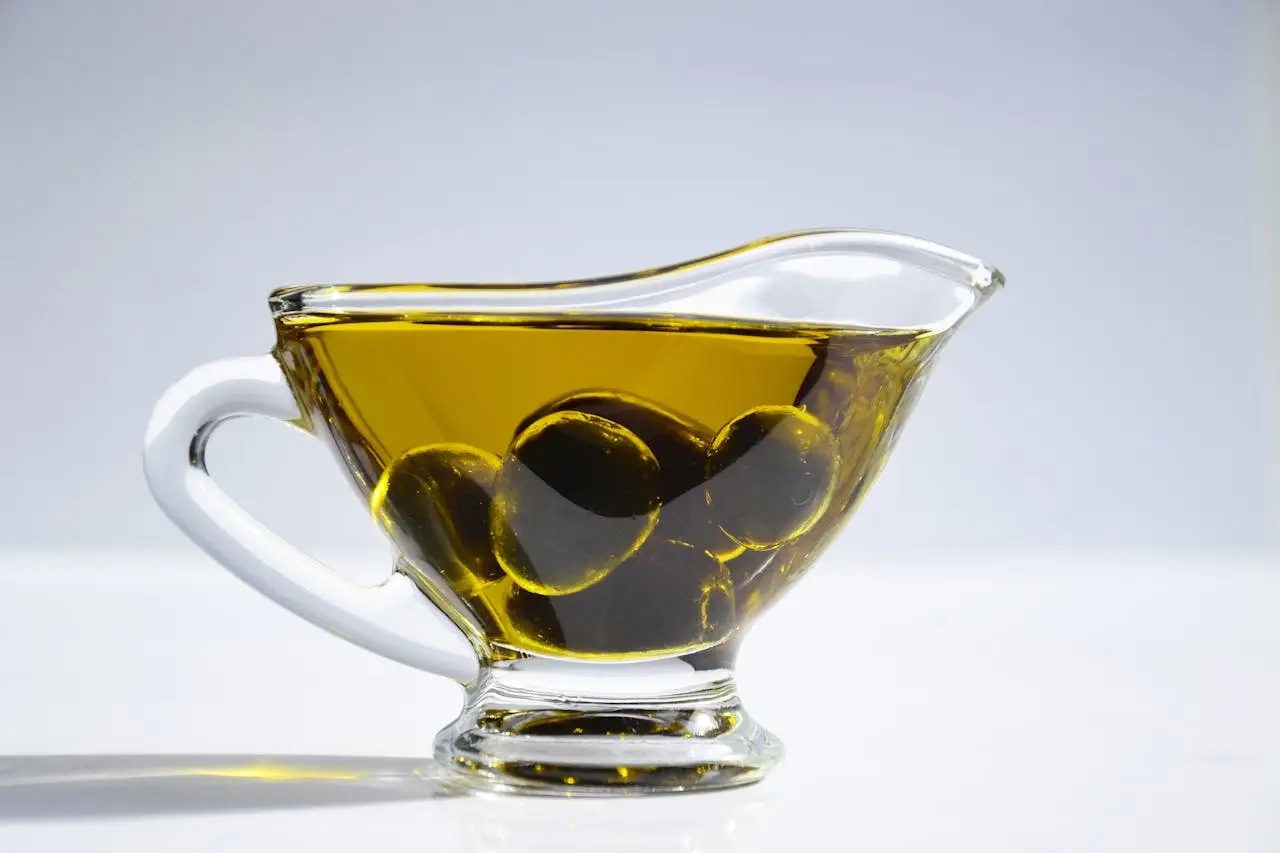 our-story High-resolution image of a glass cup filled with olive oil and olives, ideal for culinary themes.